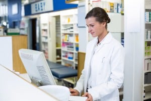 Female pharmacist stood working at computer