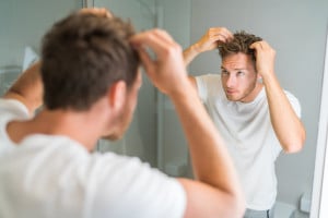 Man checking for hair loss in mirror