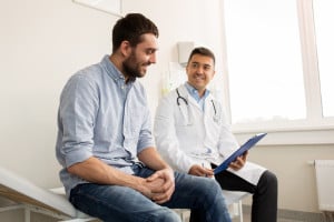 happy man talking to doctor over results on clipboard